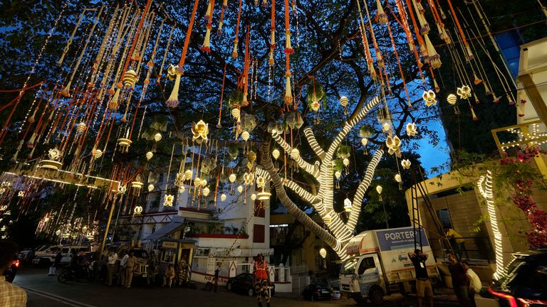 People walk past the Antilia mansion, house of billionaire Mukesh Ambani, while it is lit up ahead of his son's wedding. Pic: AP