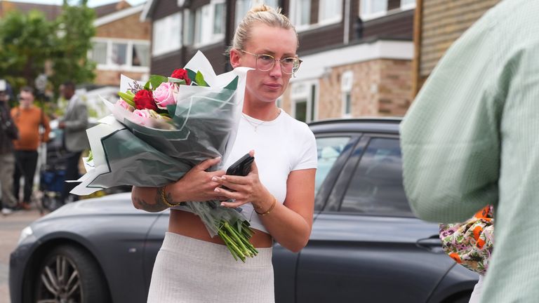 A woman arrives to leave flowers at the cordon at Ashlyn Close Pic: PA