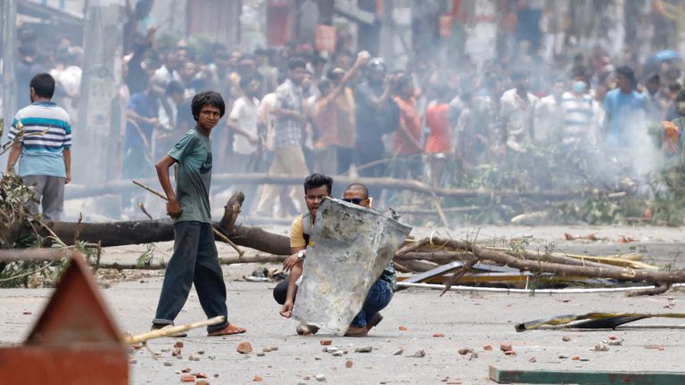 Protesters shield themselves with a metal sheet. Pic: Reuters