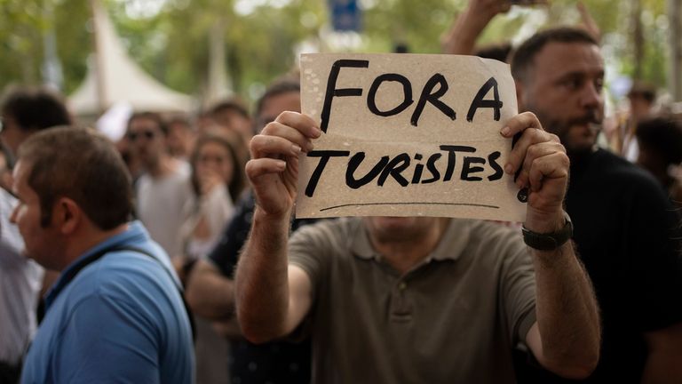 A person holds a sign during a demonstration against mass tourism on July 6, 2024, in Barcelona, Catalonia, Spain. Some 2,800 people, according to the City Council, have demonstrated in the center of Barcelona against mass tourism, under the slogan 'Enough. Let's put a limit to tourism'. The demonstrators declared that there is a tourist industry that "has enormous negative impacts, in labor, social and environmental terms". 06 JULY 2024 Lorena Sop..na / Europa Press 07/06/2024 (Europa Press via AP)