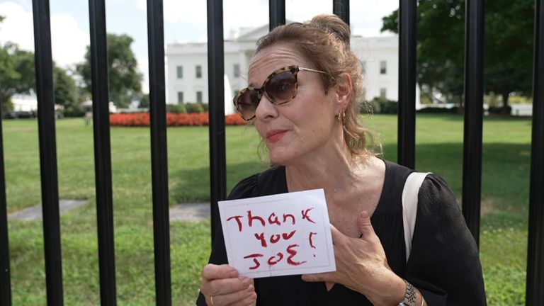 Angela Dean holds a sign outside the White House thanking Joe Biden as he steps out of the presidential race