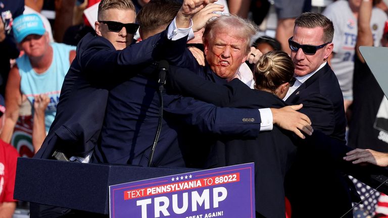 Donald Trump gestures with a bloodied face while he is assisted by U.S. Secret Service personnel.
Pic: Reuters