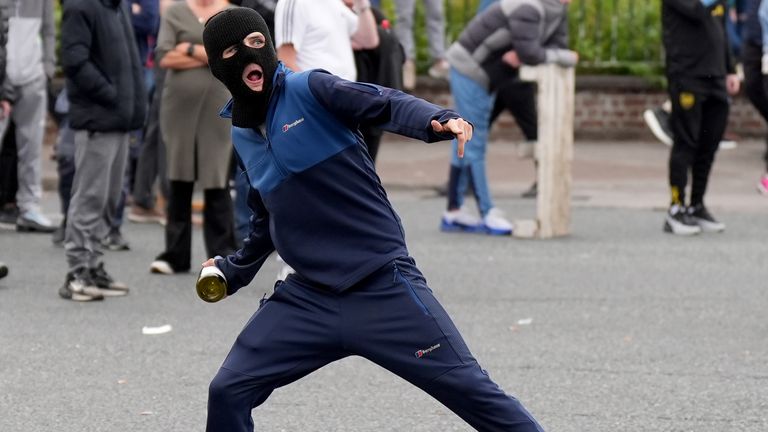 A youngster throws a bottle towards gardai officers during a stand off with protesters after a number of fires have been started at the former site of the Crown Paints factory in Coolock, north Dublin. Picture date: Monday July 15, 2024. PA Photo. The protesters have objected to the disused warehouse being redeveloped to house asylum seekers. See PA story IRISH Coolock. Photo credit should read: Niall Carson/PA Wire