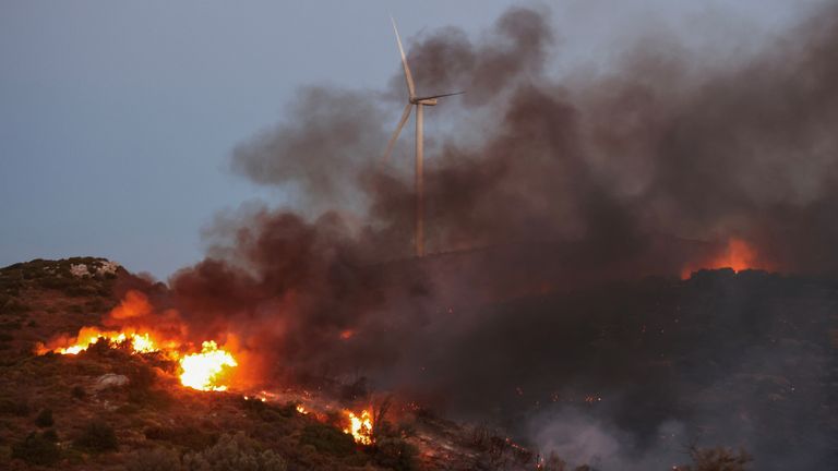 A wildfire burns next to a wind turbine near the village of Petries on the island of Evia.
Pic: Reuters