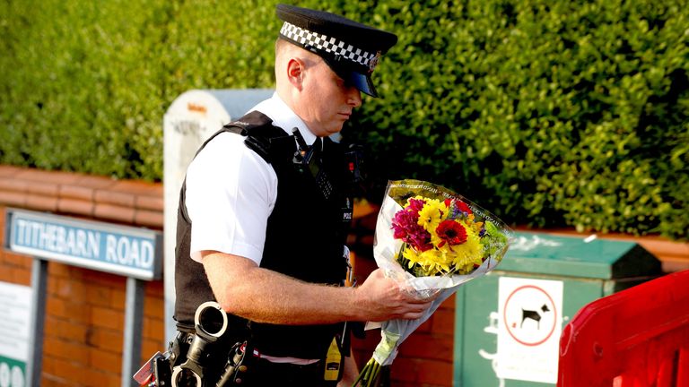 A police officer carries  flowers, given by residents, to put them behind the police cordon.
Pic: Reuters