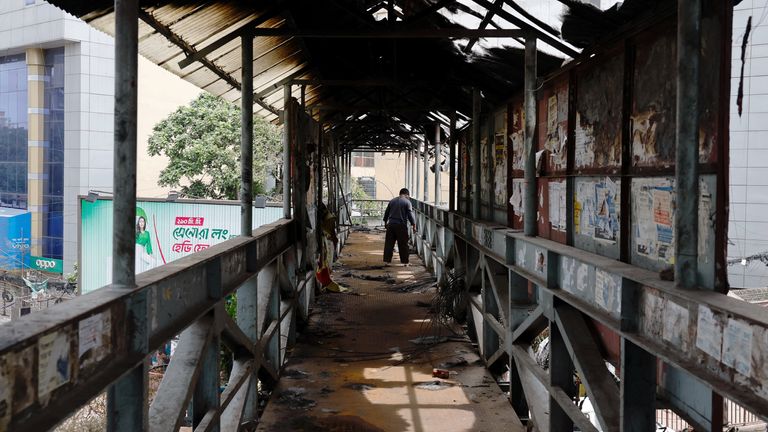 A man walks on a partially damaged footbridge