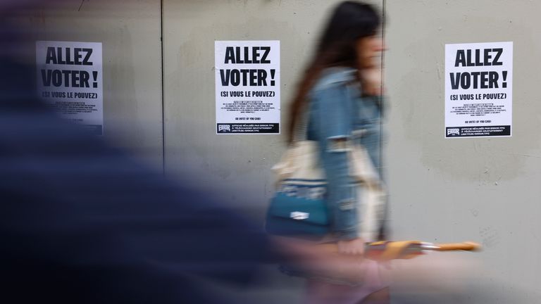 A woman walks past posters that read 'Go vote!'. Pic: AP