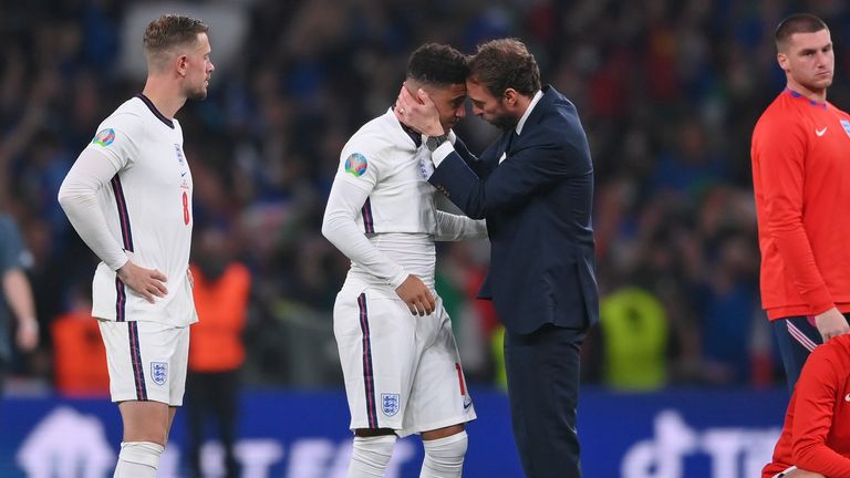 FILE - England's manager Gareth Southgate, center right, consoles England's Jadon Sancho after the penalty shootout of the Euro 2020 soccer final match between England and Italy at Wembley stadium in London, Sunday, July 11, 2021. Black players like Marcus Rashford and Bukayo Saka have flourished even after being targeted online for missing penalties in England's shootout loss to Italy in the European Championship final in 2020. But a third Black player who also missed a penalty and was racially abused, Jadon Sancho, has struggled on the field ever since. (Laurence Griffiths/Pool via AP, File)