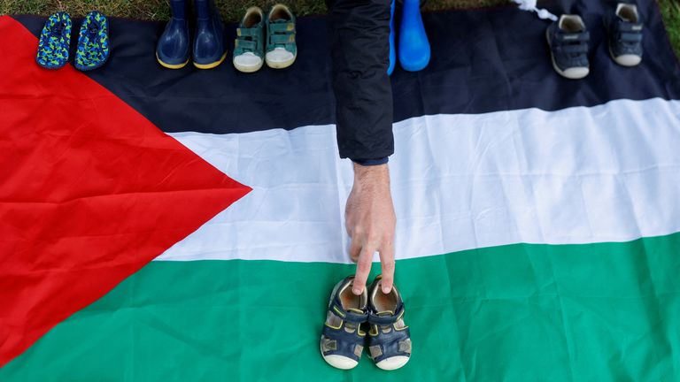A healthcare worker places baby shoes on a Palestinian flag during a vigil to remember and read out the names of the children who have been killed in Gaza, outside the U.S. embassy, amidst the ongoing conflict between Israel and Hamas, in Dublin, Ireland, June 8, 2024. REUTERS/Clodagh Kilcoyne TPX IMAGES OF THE DAY