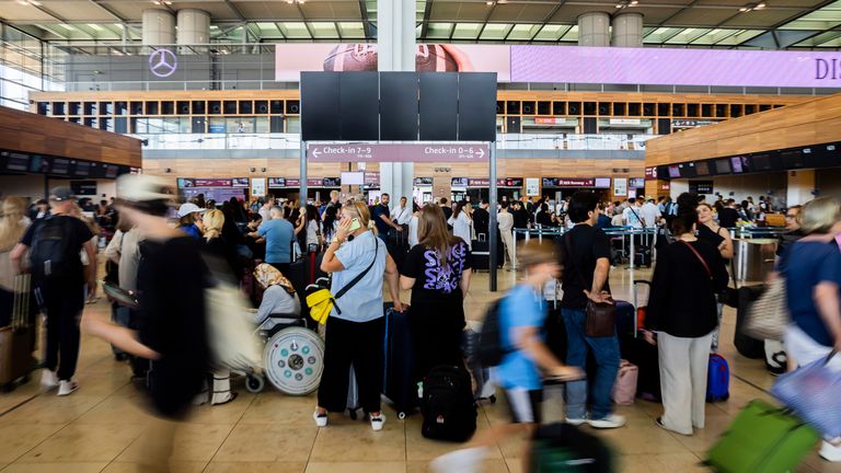 Numerous passengers wait in front of a black display board at the capital&#39;s Berlin Brandenburg Airport, in Schönefeld, Germany, Friday July 19, 2024. Air traffic has been suspended at BER Airport. A widespread Microsoft outage was disrupting flights, banks, media outlets and companies around the world on Friday. (Christoph Soeder/dpa via AP)