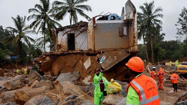 A volunteer throws a bottle of water to a man during rescue operations after several landslides hit the hills in Wayanad district, in the southern state of Kerala, India, July 31, 2024. REUTERS/Francis Mascarenhas