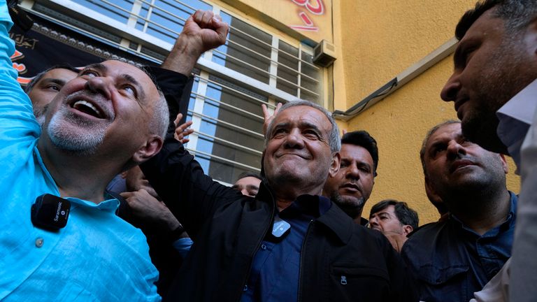 Reformist candidate for the Iran's presidential election Masoud Pezeshkian clenches his fist after casting his vote as he is accompanied by former Foreign Minister Mohammad Javad Zarif, left, at a polling station in Shahr-e-Qods near Tehran, Iran, Friday, July 5, 2024. Iranians are voting in a runoff election to replace the late President Ebrahim Raisi, who was killed in a May helicopter crash in the country...s northwest along with the foreign minister and several other officials. (AP Photo/Vahid Salemi)