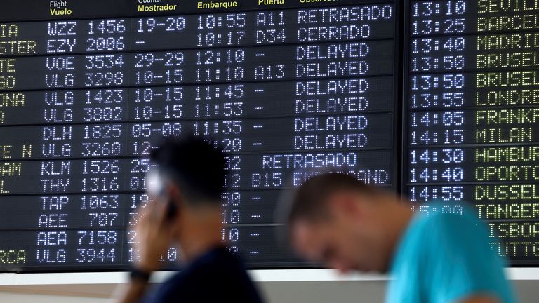 Passengers wait in front of a board displaying delayed flight information, at Bilbao Airport in Bilbao, Spain, July 19, 2024. Spanish airport operator Aena AENA.MC reported a computer systems "incident" at all Spanish airports which may cause flight delays. REUTERS/Vincent West