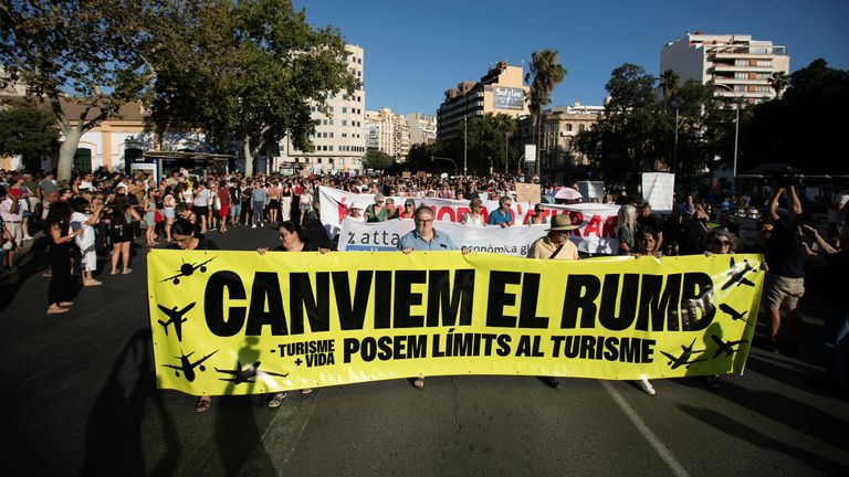 A banner reads: 'Let's change course, let's put limits on tourism'. Pic: Reuters