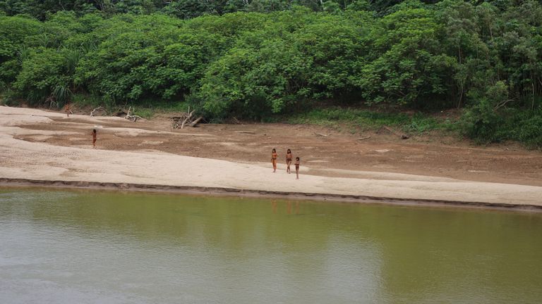 Members of the tribe on the banks of the river. Pic: Survival International via Reuters