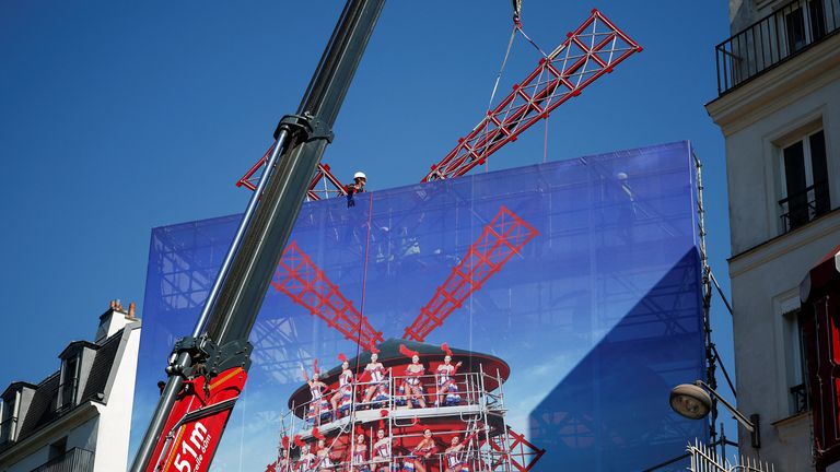 A crane lifts one of the four new windmill sails to install it atop the Moulin Rouge, Paris' most famous cabaret club, after its sails fell off in Paris, France, June 24, 2024. REUTERS/Benoit Tessier