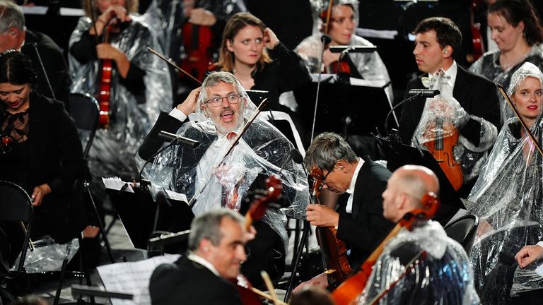 Musicians from the French National Orchestra shelter from the rain during the opening ceremony.
Pic:PA