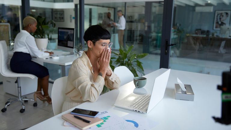 Woman sneezing in an office. Pic: iStock