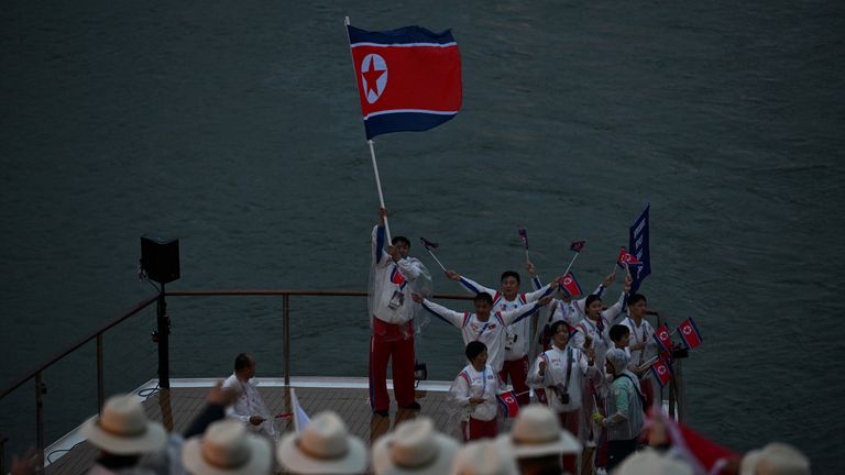 North Korean delegates wave their flag as they travel along the River Seine ahead of the opening ceremony in Paris. Pic: Reuters