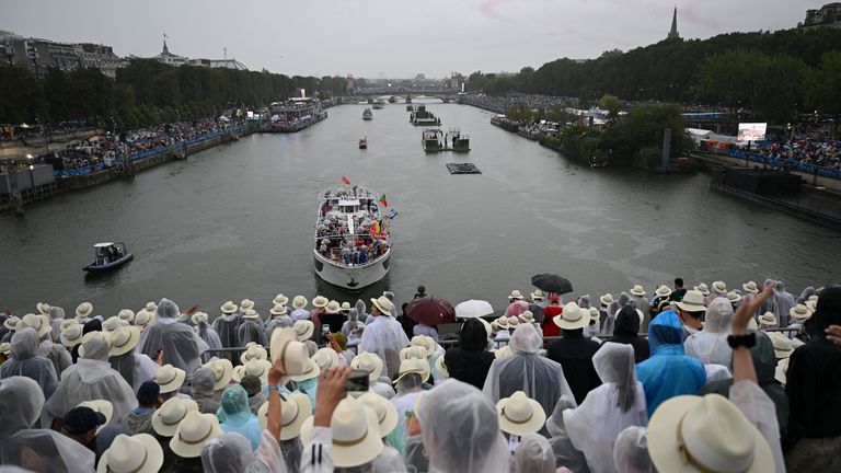 Spectators watch Olympic delegates go past along the Seine in Paris. Pic: Reuters