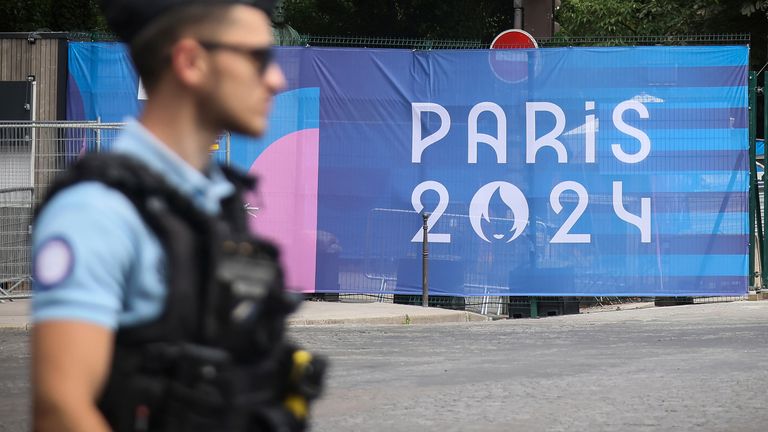 A police officer walks past a Paris Olympics canvas. Pic: AP