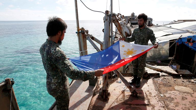 Philippine Marines fold a Philippine national flag during a flag retreat at the BRP Sierra Madre, 