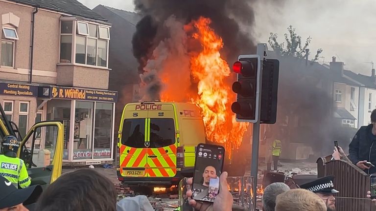 A police van set is seen of fire as trouble flares during a protest in Southport