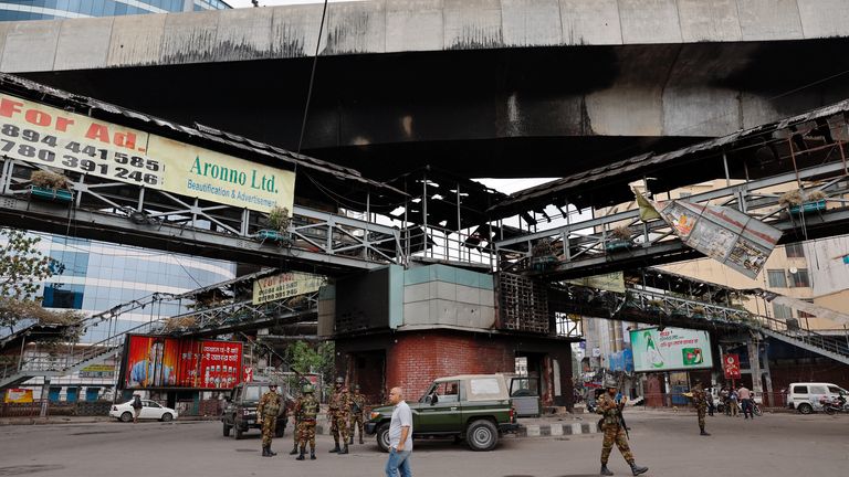 Soldiers stand guard under a footbridge that was set on fire 