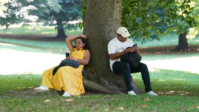 People sit in the shade beneath a tree during hot weather in St James's Park.
Pic: Reuters