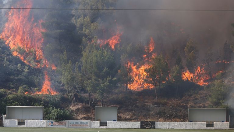 Flames rise next to a football stadium as a wildfire burns in Stamata.
Pic:Reuters