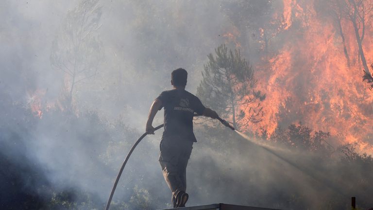 A volunteer tries to extinguish a wildfire burning in Stamata.
Pic: Reuters