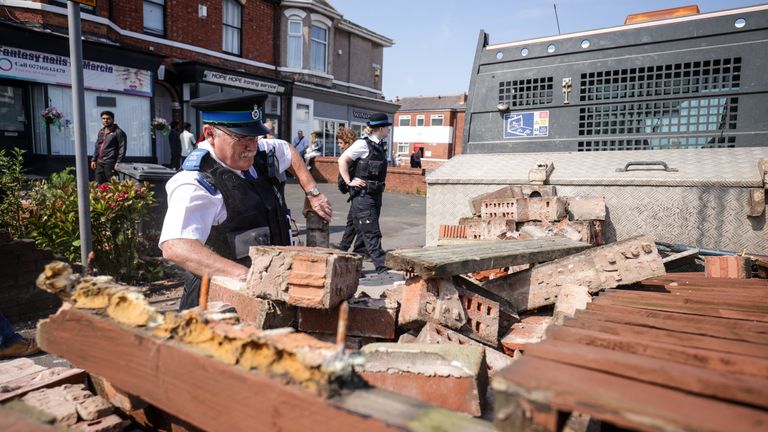 A community police officer removes bricks from a damaged wall in Sussex Road.  Photo: PA