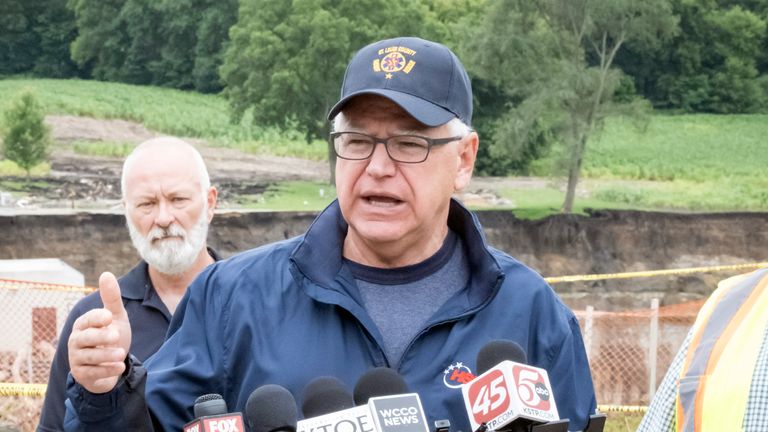 Minnesota Governor Tim Walz addresses the media Tuesday, July 2, 2024, at the Rapidan Dam in Rapidan, Minnesota.  The rushing waters of the Blue Earth River have already left a trail of debris and destruction on the edges of a dam in southern Minnesota that partially failed last week.  (Casey Ek/The Free Press via AP)