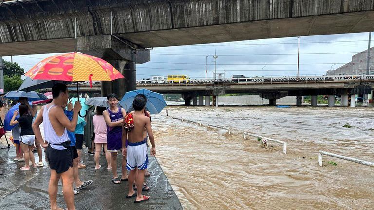 CORRECTS PHOTOGRAPHER'S LAST NAME TO CALUPITAN - Residents watch the Marikina river as it floods from monsoon rains worsened by offshore typhoon Gaemi on Wednesday, July 24, 2024, near Manila, Philippines. (AP Photo/Joeal Calupitan)