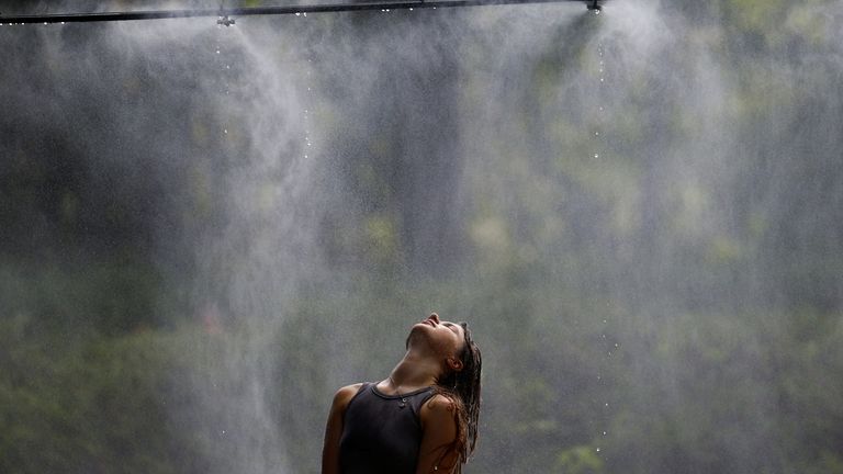 A woman cools herself off under a water sprinkler in central Kyiv amid a heatwave. Pic: Reuters