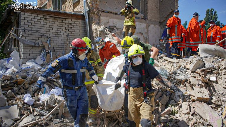 Rescuers carry a body through the rubble of an apartment building struck by a missile in Kyiv on Tuesday. Pic: Reuters