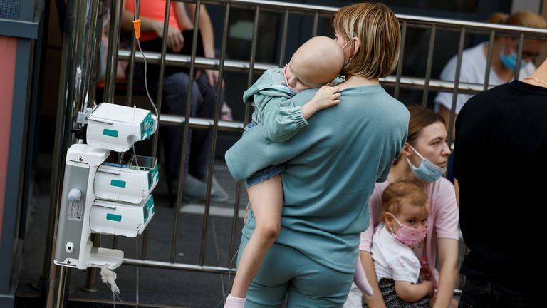 A woman carries her child near the Okhmatdyt children's hospital. Pic: Reuters 