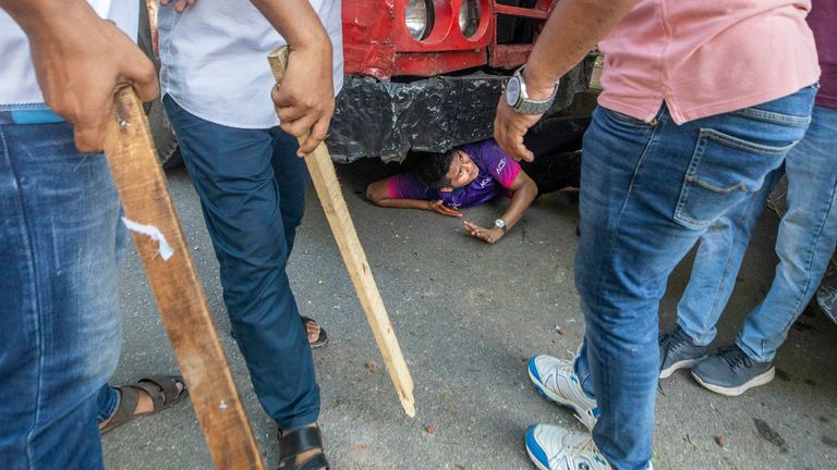 A student hides beneath a vechicle as students clash over quota system at Jahangir Nagar University at Savar outside Dhaka, Bangladesh, Monday, July 15, 2024. Police have fired tear gas and charged with batons overnight during violent clashes between a pro-government student body and student protesters, leaving dozens injured at a leading public university outside Bangladesh's capital over quota system in government jobs, police and students said Tuesday.(AP Photo/Abdul Goni)