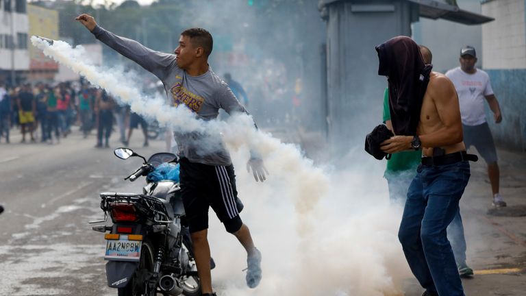 A protester throws a gas canister back at police. Pic: AP