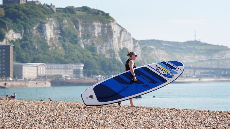 A lady prepares to paddleboard during the warm weather on the beach in Dover, Kent. South-eastern England is likely to see the UK's hottest day of the year far on Friday, although the UK as a whole will face a mixed picture on Friday and into the weekend. Picture date: Friday July 19, 2024. Pic: PA 