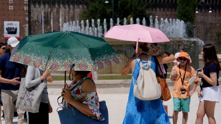 Tourists shelter from the sun in front of the Sforzesco Castle in Milan. Pic: AP