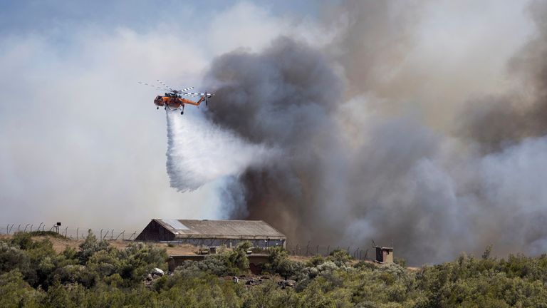 A helicopter drops water over a wildfire at Keratea.
Pic: AP