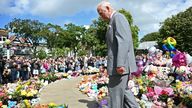 The King reacts as he views tributes outside Southport Town Hall. Pic: PA