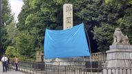 A blue sheet covers a stone pillar on which graffiti was found. Pic: Kyodo News via AP