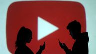Silhouettes of mobile users are seen next to a screen projection of Youtube logo in this picture illustration taken March 28, 2018. REUTERS/Dado Ruvic/Illustration