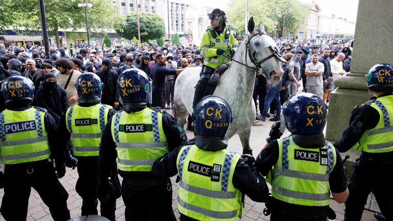 Police officers stand guard next to counter-protesters, on the day of a protest against illegal immigration, in Bolton, on Sunday 4 August. Pic: Reuters