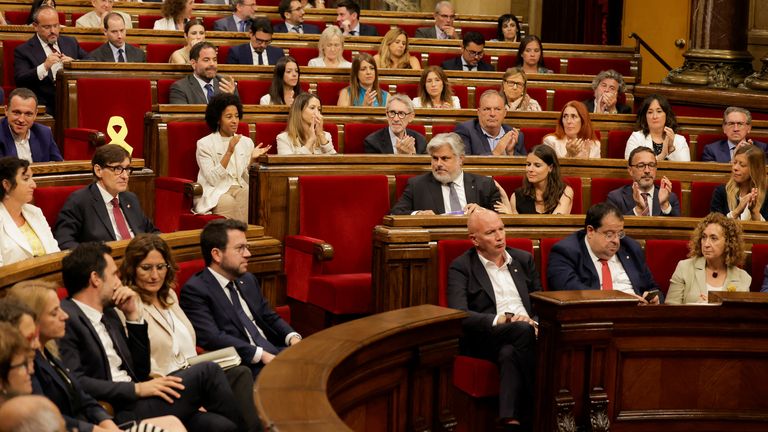 Socialist Party of Catalonia (PSC) candidate Salvador Illa and Member of Parliament Albert Batet flank Catalan separatist leader Carles Puigdemont's empty chair at the Catalonia Regional Parliament, on the day of the investiture debate to elect a new leader, in Barcelona, Spain, August 8, 2024. REUTERS/Jon Nazca
