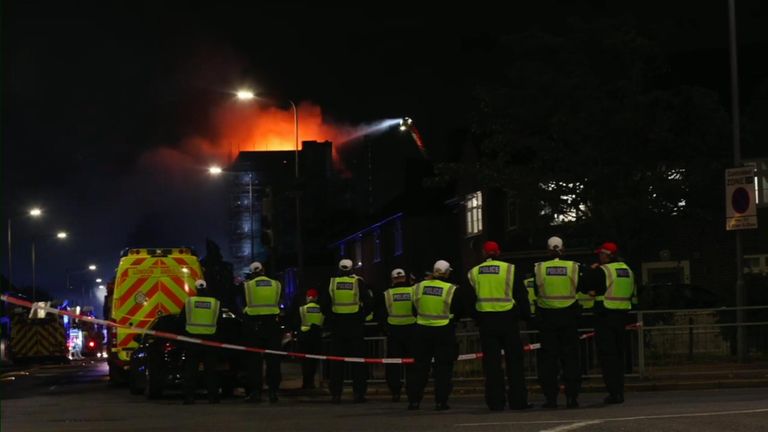 Police watch on as the fire rages