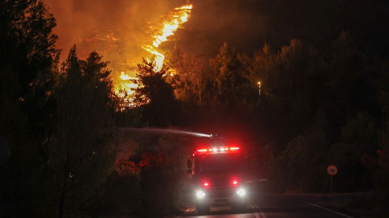 Firefighters try to extinguish a wildfire burning in Dionysos.
Pic: Reuters