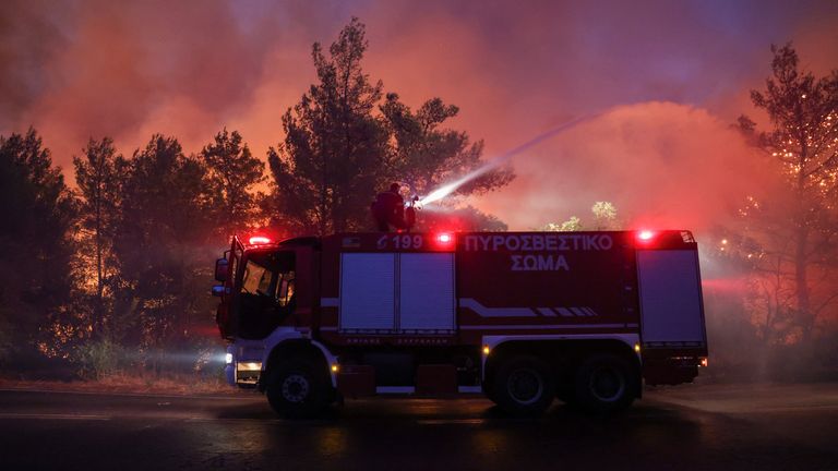 Firefighters try to extinguish a wildfire burning in Dionysos.
Pic: Reuters